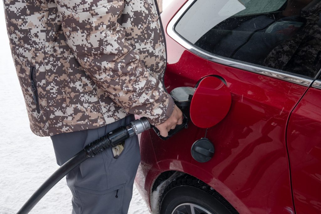 man holding fuel pump nozzle with filling benzine oil in red car on winter in self service petrol station coaching,financier,conseils,faire des,écconomies