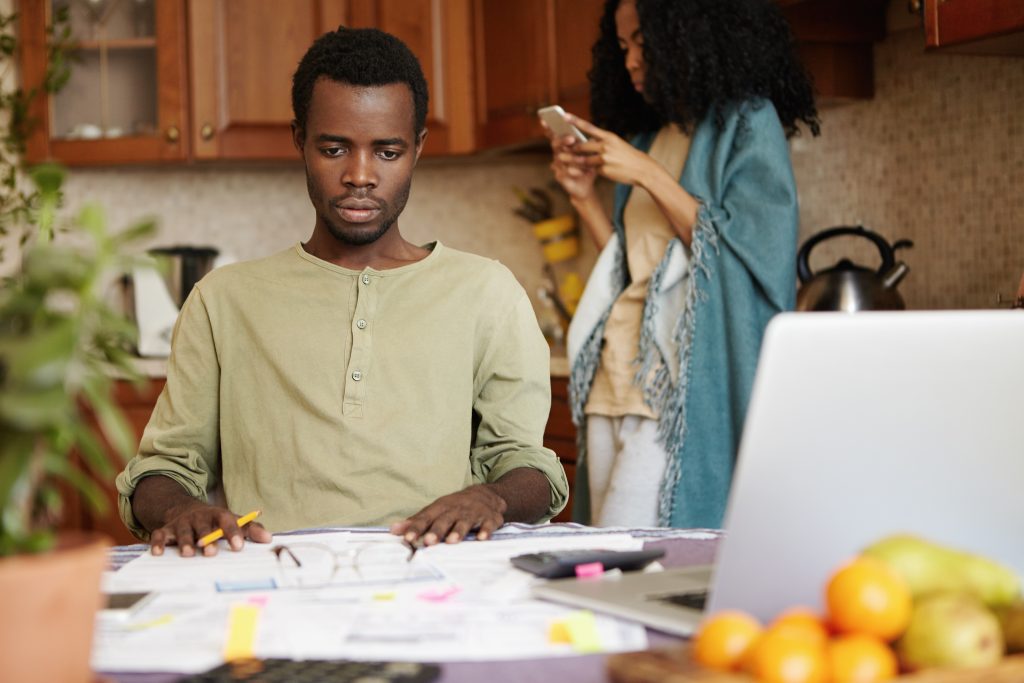 young african couple with many debts facing financial stress petrified husband looking ahead of him in complete shock realizing that his family is not able to pay for rent forced to move out